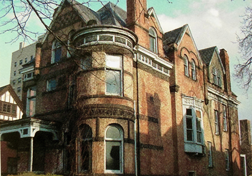 Old orange brick Victorian-style home with ivy