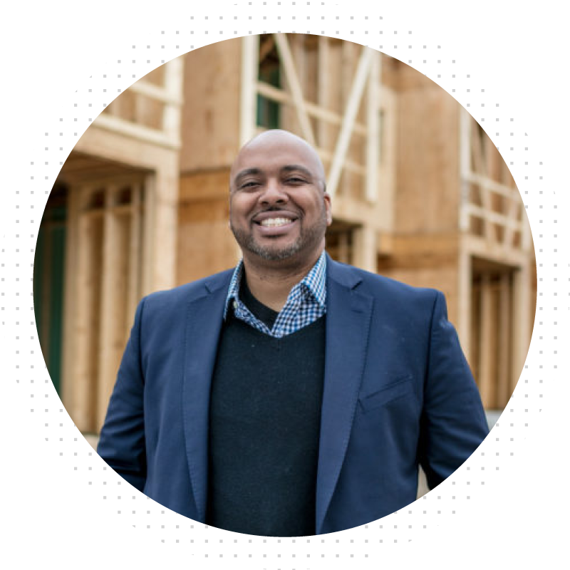Man smiling at camera in front of wooden framed building